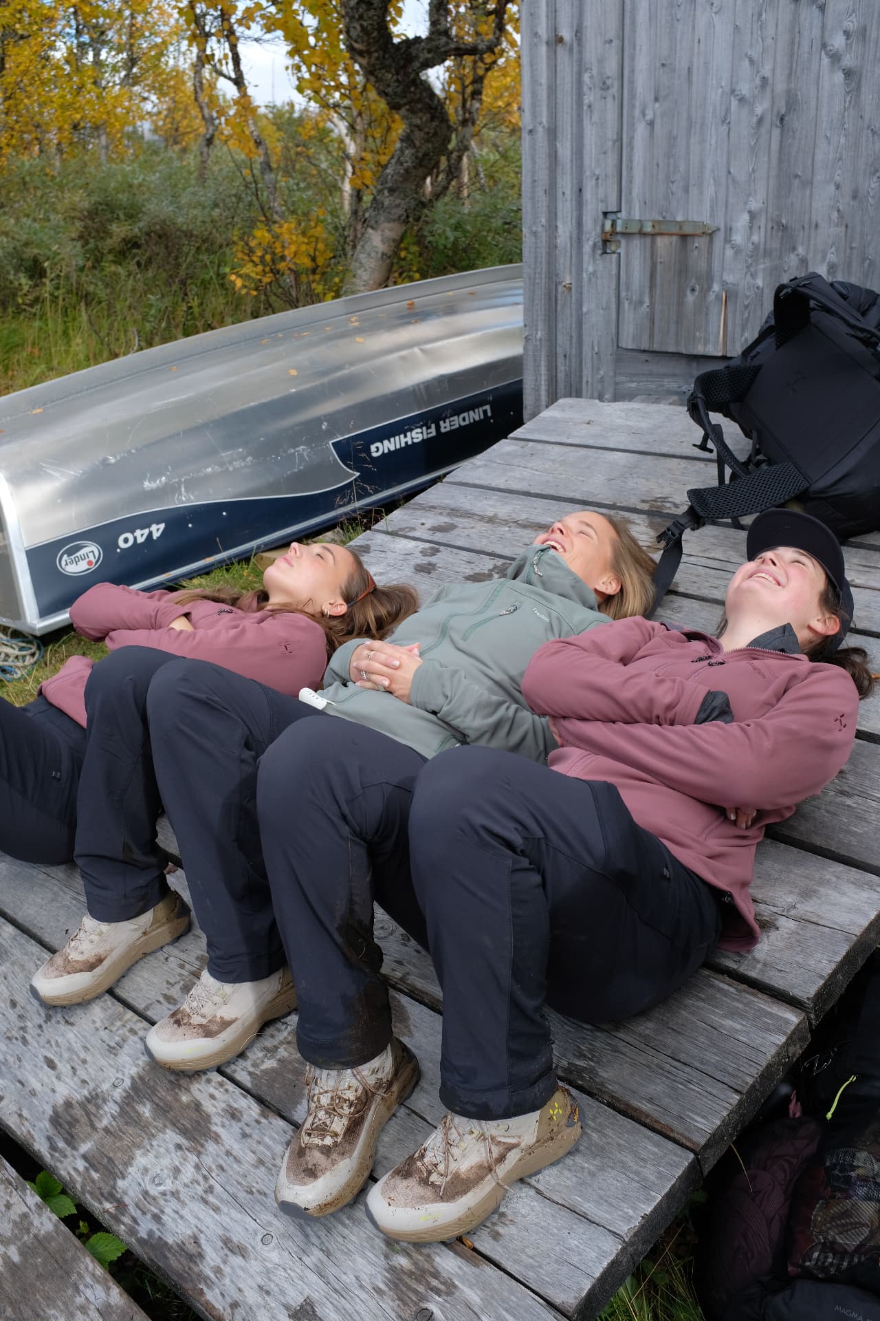 Tre vandrare vilar skrattande på en brygga vid fjällstugan