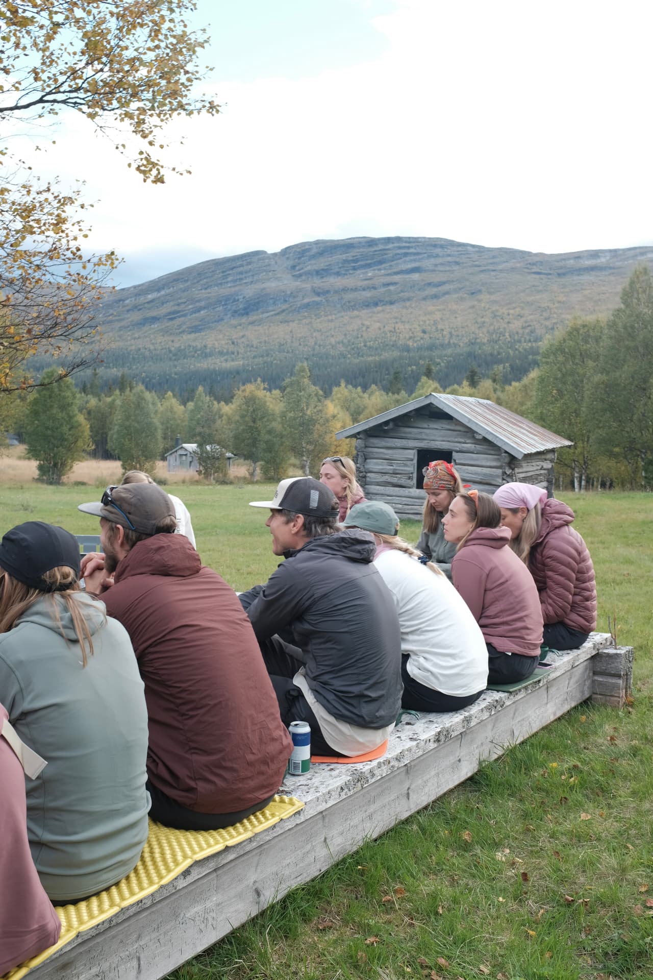 Gruppen sitter samlad på en träbrygga med fjällen i bakgrunden